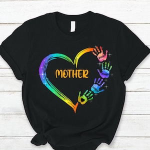 Pu&ograve; includere: Maglietta nera con un cuore arcobaleno e impronte di mani. Il cuore contiene la parola "MAMMA". Le impronte di mani sono etichettate Jaidyn, Bobby e Theresa.
