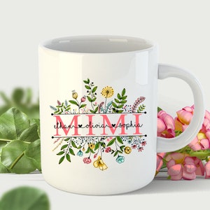 May include: White ceramic mug with a floral design and the word "MIMI" in pink letters. Below the word "MIMI" are the names "Ethan", "Olivia", and "Sophia" with hearts between each name.