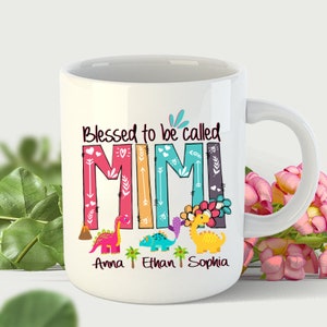 May include: White ceramic mug with a colorful design featuring the word "MIMI" with a dinosaur theme. The text "Blessed to be called" is above the word "MIMI". The names "Anna", "Ethan", and "Sophia" are written below the word "MIMI".