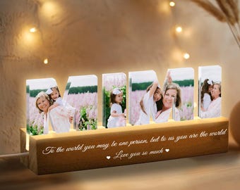 Puede incluir: Un letrero luminoso de madera con la palabra "MIMI" escrita en letras de acrílico transparente. Cada letra tiene una foto diferente de una mujer y un niño. El letrero tiene un mensaje que dice: "Para el mundo puedes ser una sola persona, pero para nosotros eres el mundo. Te queremos mucho."