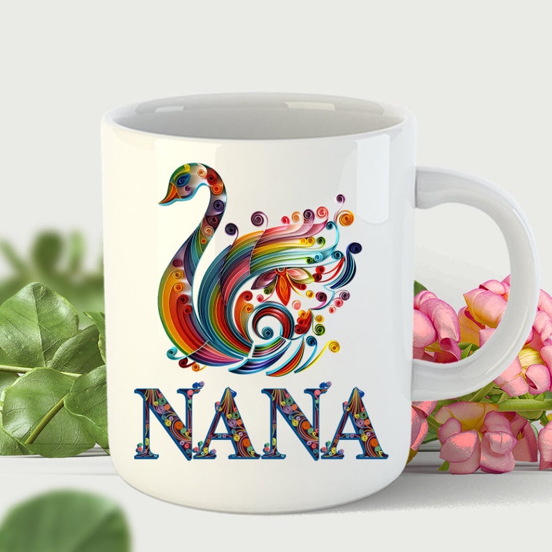 May include: White ceramic mug with a colorful paper quilling design of a swan and the word "NANA" in colorful letters.