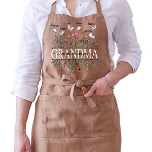 May include: A brown apron with a floral design and butterflies. The text "Grandma I love you" is printed on the apron. The butterflies have names printed on them.
