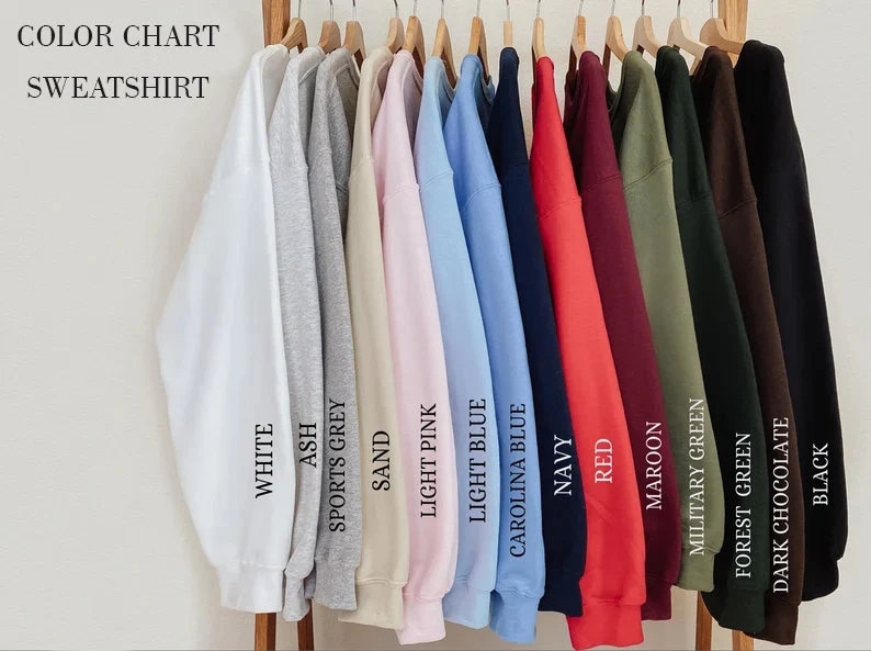 May include: Color chart showing 12 different sweatshirt colors, including white, ash, sports grey, sand, light pink, light blue, Carolina blue, navy, red, maroon, military green, forest green, dark chocolate, and black.