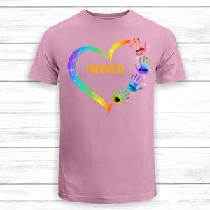 Pu&ograve; includere: Maglietta rosa con un design a forma di cuore arcobaleno e impronte di mani. Le impronte di mani hanno i nomi scritti su di esse: Jaidra, Bobby e Theresa. Il cuore ha la parola "MAMMA" scritta al suo interno.