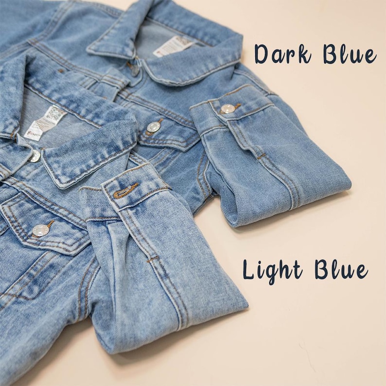 Puede incluir: Dos chaquetas vaqueras, una azul oscuro y otra azul claro, est&aacute;n dispuestas sobre una superficie beige. Las chaquetas est&aacute;n dobladas por la mitad, con las mangas dobladas sobre la parte delantera de las chaquetas.