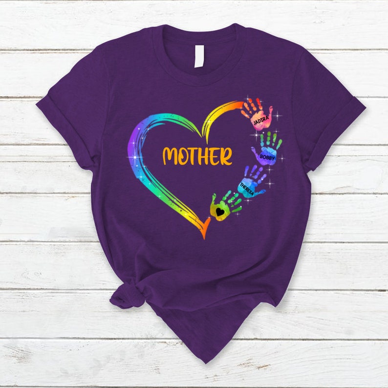 Pu&ograve; includere: Maglietta viola con un cuore arcobaleno e impronte di mani. Le impronte di mani hanno nomi scritti su di esse: Jaidira, Bobby e Theresa. Il cuore ha la parola "MAMMA" scritta all'interno.