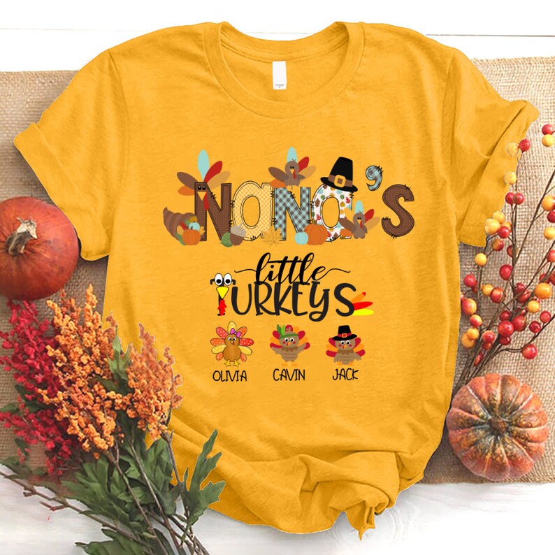 May include: Yellow t-shirt with a Thanksgiving theme. The text "NANA'S little TURKEYS" is printed on the shirt. There are three turkeys with the names Olivia, Cavin, and Jack printed below them.