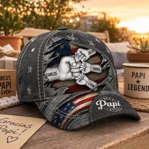 May include: A gray baseball cap with a distressed American flag design. The cap features a graphic of hands clasped together with the names Carlos, Jacob, Emma, and Liam. The text "Best Papi Ever" is on the cap.