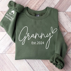 May include: A green sweatshirt with the text "Granny Est. 2024" in white lettering. A small heart is next to the word "Granny".