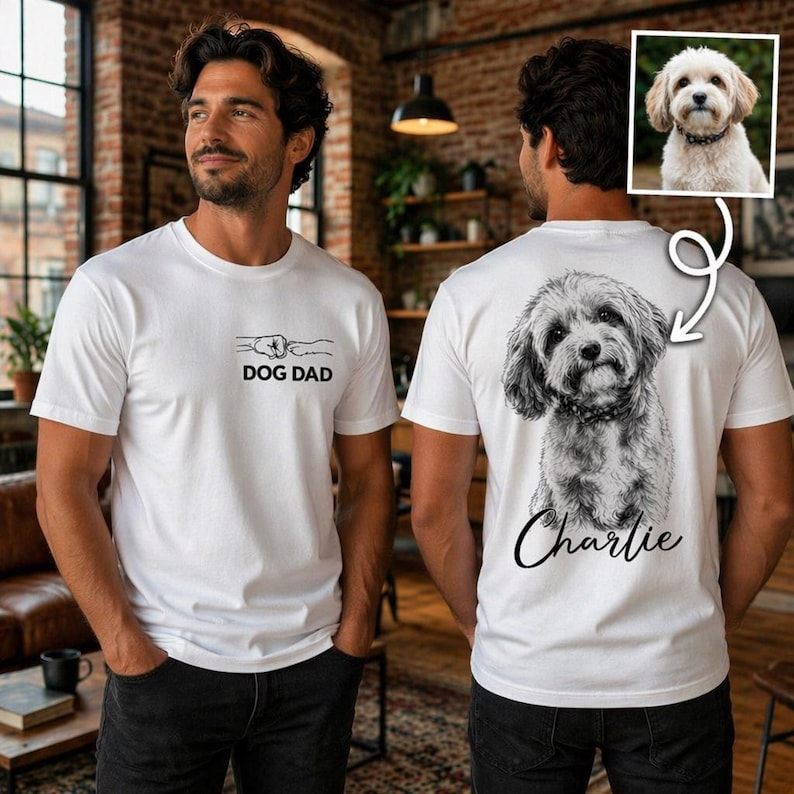 Pode incluir: Uma t-shirt branca com um pequeno gr&aacute;fico no peito mostrando um toque de punho e pata com o texto DOG DAD. A parte de tr&aacute;s da t-shirt apresenta um esbo&ccedil;o grande e detalhado a preto e branco de um c&atilde;o peludo com o nome Charlie abaixo.