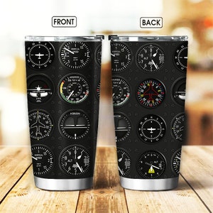 May include: A stainless steel tumbler with a black and white design featuring various airplane cockpit instruments. The instruments include a compass, altimeter, airspeed indicator, and vertical speed indicator. The tumbler has a silver lid and a silver base.