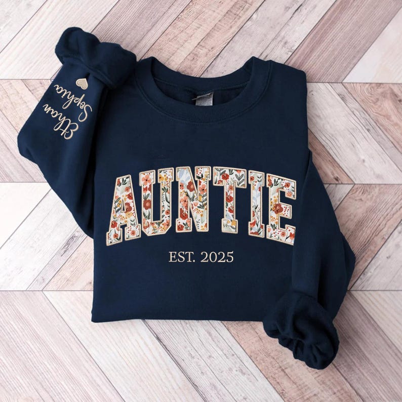 May include: Navy blue sweatshirt with a floral print "AUNTIE" design and the text "EST. 2025".