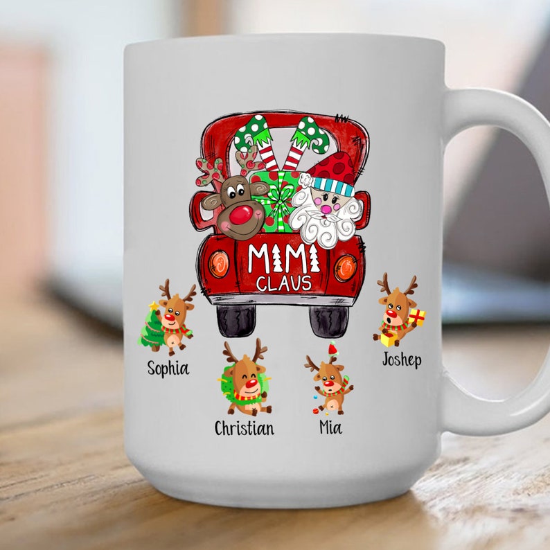 May include: White ceramic mug with a red truck design featuring Santa Claus and reindeer. The truck has the text "MIMI CLAUS" on the back. There are five reindeer with names below them: Sophia, Christian, Mia, Joshep.