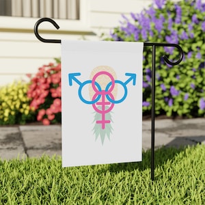 May include: A white garden flag with a pink and blue gender symbol design inside a pineapple graphic.