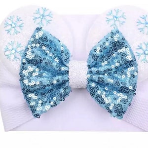 May include: White headband with a large blue sequin bow and snowflake embroidery.