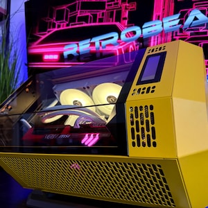 May include: A yellow computer case with a transparent top, showcasing internal components illuminated by white lights. The case has a mesh front panel and a small display screen. The background features the word "RETROBEASTS" in neon pink.