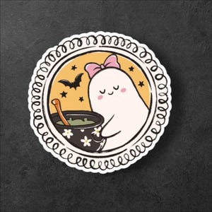 May include: A circular sticker featuring a cute ghost with a pink bow, holding a cauldron of green liquid. The ghost is inside a yellow circle with a black bat and stars. The sticker has a white, decorative border and is on a dark background.