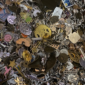 May include: A large collection of assorted metal charms, including keys, stars, hearts, and zodiac signs. The charms are in various shades of silver and gold, and some have intricate designs.