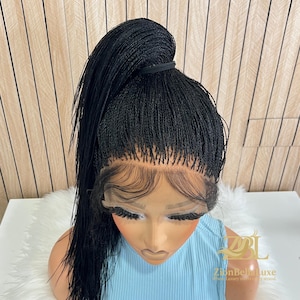 May include: A black micro braid wig styled in a high ponytail. The wig features a lace front and is displayed on a mannequin head wearing a light blue top. The wig is styled with a sleek, natural hairline.