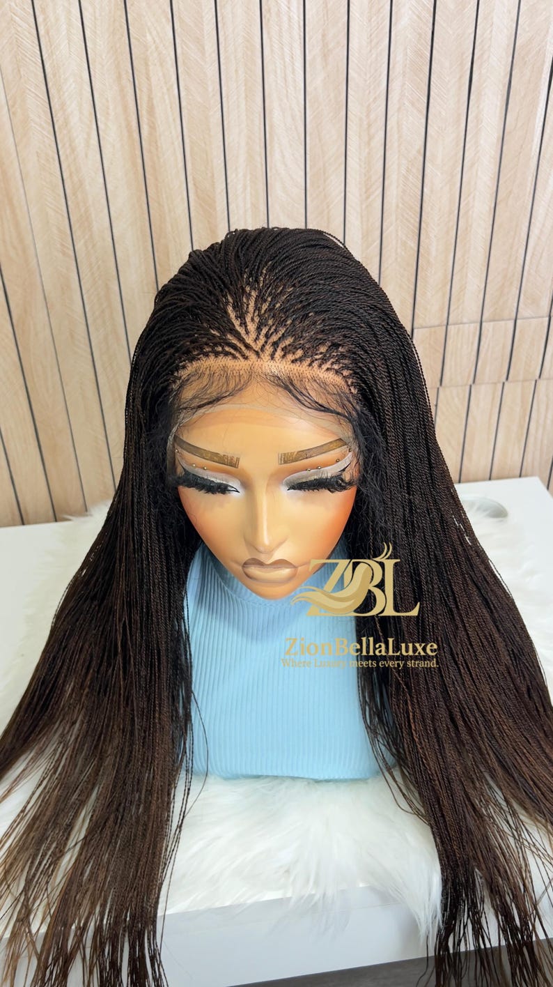 Op de afbeelding: Een donkerbruine lace front pruik met micro-vlechtjes, een gedefinieerde middenscheiding en babyhaartjes langs de haarlijn. De pruik wordt getoond op een etalagepophoofd met het logo ZBL Zion BellaLuxe Where Luxury meets every strand.