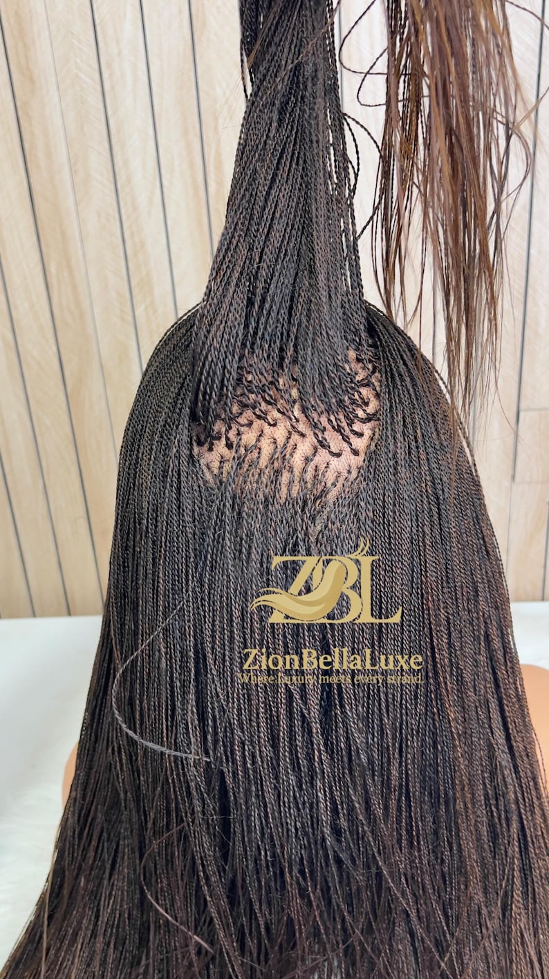 Op de afbeelding: Een donkerbruine pruik met talloze dunne, micro-gevlochten strengen gestyled in een hoge paardenstaart. De basis toont een zichtbaar hoofdhuidgedeelte waar de vlechten zijn bevestigd. Een gouden logo leest ZBL ZionBellaLuxe Where luxury meets every strand.