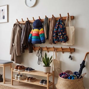 Peut inclure: Un porte-manteau mural en bois à deux rails horizontaux avec de multiples patères. Il supporte divers manteaux, une doudoune rayée arc-en-ciel, des écharpes, un sac fourre-tout et des clés. Un meuble à chaussures en bois est placé en dessous.