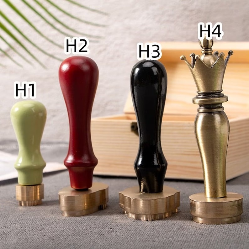 May include: Four wax seal stamps with wooden handles. The handles are in green, red, and black, with a brass-colored stamp base. The fourth stamp has a brass-colored king chess piece design.