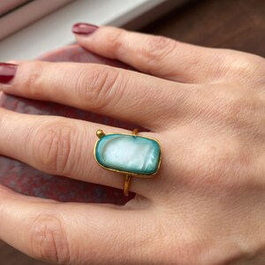 May include: A gold ring with a rectangular turquoise and white stone.