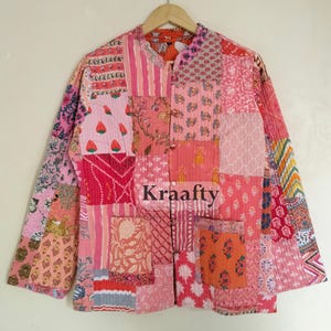 May include: A patchwork jacket in shades of pink, red, and orange, with a variety of floral and geometric patterns. The jacket has long sleeves, a mandarin collar, and two front pockets. The word "Kraafty" is visible on the front.
