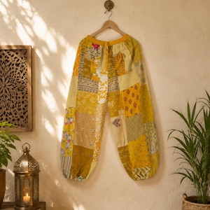 Könnte beinhalten: Weit geschnittene Hose mit Patchwork-Design in verschiedenen Gelb-, Gold- und Cremetönen. Das Kleidungsstück verfügt über einen elastischen Bund mit Kordelzug, geraffte Beinabschlüsse sowie eine Mischung aus floralen und geometrischen Mustern.