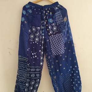 May include: Blue patchwork pants with a drawstring waist. The pants feature various patterns, including circles, squares, and floral designs. The fabric appears to be lightweight, suitable for casual wear.