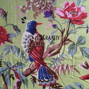 Puede incluir: Tela estampada con un patrón repetido de un pájaro colorido posado en una rama, rodeado de grandes flores rojas y rosas, hojas verdes y ramas marrones. El pájaro tiene plumas azules, rojas y marrones. El fondo es verde claro.