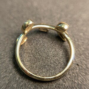 May include: Gold ring with three round stones set in the band. The ring is open and has a unique design.