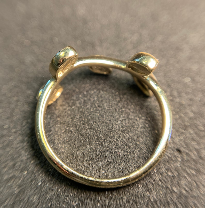 May include: Gold ring with three round stones set in the band. The ring is open and has a unique design.