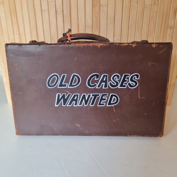 Vintage brown leather suitcase featuring handpainted letters that say "Old Cases Wanted."