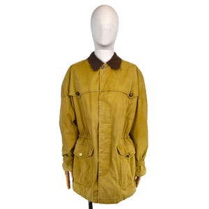 May include: A mustard-colored jacket with a brown corduroy collar. The jacket has two front pockets, two chest pockets, and gold-colored buttons. The jacket is displayed on a mannequin.