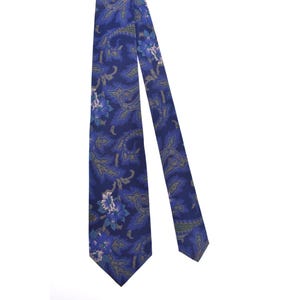 Pode incluir: Uma gravata azul paisley com um padrão floral. A gravata apresenta um fundo azul escuro com desenhos florais e paisley em azul claro, branco e bege. A gravata está em ângulo diagonalmente contra um fundo branco.