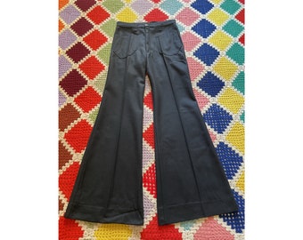 May include: Black wide-leg pants with a high waist and a flared silhouette. The pants have a simple design with two pockets on the front.