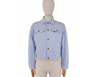 May include: Light blue denim jacket with long sleeves, two chest pockets, and button closures. The jacket is displayed on a mannequin. The jacket has a classic design and is made of a light-wash denim material.