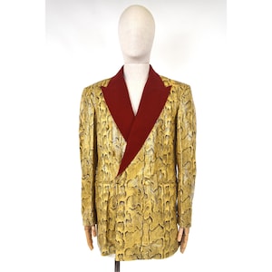 May include: A snakeskin-effect blazer in yellow and black, with a burgundy lapel, displayed on a mannequin. The jacket has a classic cut with a two-button closure and a notched lapel. The snakeskin pattern is a mix of yellow, gold, and black.