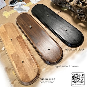 May include: Three wooden display plaques in natural oiled beechwood, aged walnut brown, and ebonized black. Each plaque has a rounded rectangular shape with a brass-coloured mounting hole.
