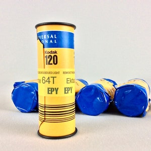 May include: A yellow and blue roll of Kodak 120 film. The film is labeled "Kodak 120" and "64T EPY".