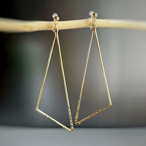 May include: A pair of gold triangle shaped earrings with a hammered texture.
