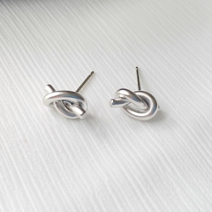 May include: A pair of silver knot-shaped stud earrings. The earrings are simple and elegant, and would make a great gift for any occasion.