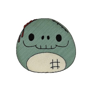 May include: A green and white embroidered patch of a cartoon zombie with a stitched-up mouth and a skull face. The zombie has a stitched-up belly button.