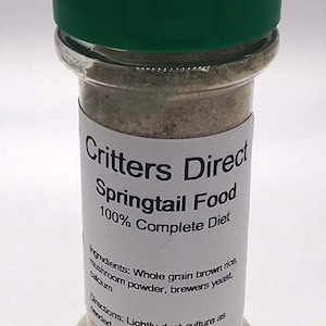 May include: A clear plastic jar with a green lid filled with a light brown powder. The label reads "Critters Direct Springtail Food 100% Complete Diet" and lists the ingredients: "Whole grain brown rice, mushroom powder, brewers yeast, calcium". The label also includes directions: "Lightly dust culture as needed."