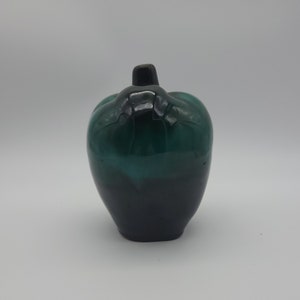 Puede incluir: Un jarrón de cerámica verde y negro con forma de pimiento. El jarrón está esmaltado en color verde oscuro y negro.