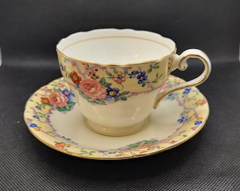 May include: A vintage teacup and saucer set with a floral pattern in shades of pink, yellow, blue, and green. The cup and saucer have a gold trim.