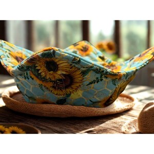 May include: A fabric bowl featuring a sunflower pattern. The bowl has a light blue backdrop with yellow sunflowers and a honeycomb design. It rests on a round, woven coaster on a wooden table. The bowl is open and has a distinctive shape.