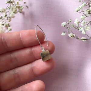 Peut inclure: Une paire de boucles d'oreilles pendantes en argent avec un pendentif en pierre carrée brun et blanc.